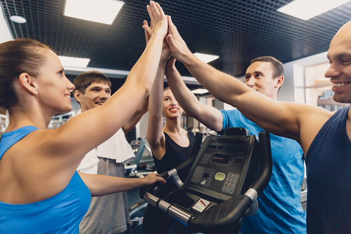 Group of people giving high-fives in a gym.