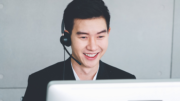 Wearing a headset in front of a computer.