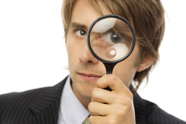 Man looking through a magnifying glass.
