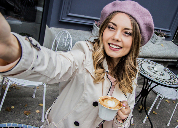 Young woman taking a selfie while drinking a coffee.