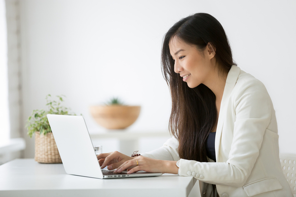 Woman typing on a laptop computer.