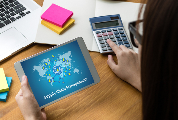 Woman looking at a tablet and using a calculator.