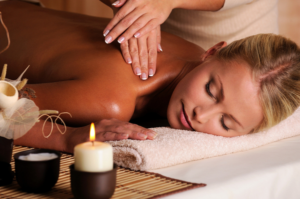 Woman lying down having a massage with a candle burning.